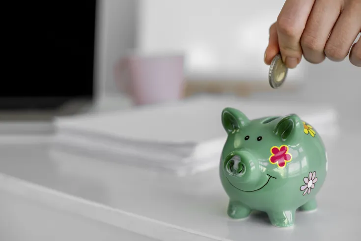 Ręka wrzucająca monetę do skarbonki