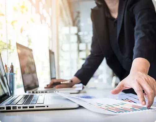 Kobieta przeglądająca dokumenty przy laptopie